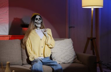 İnsan iskelet modeli, kadın gibi giyinmiş, geceleri oturma odasında oturuyor.