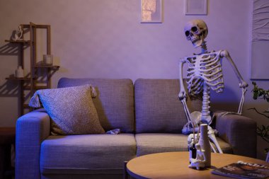 Geceleri oturma odasındaki koltukta oturan insan iskelet modeli.