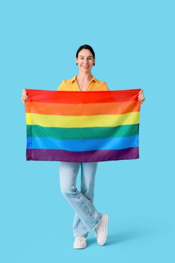 Mavi arka planda kulak tünelleri ve LGBT bayrağı olan genç bir kadın.