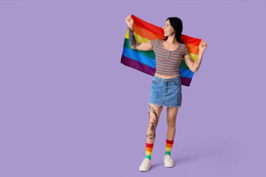 Leylak arka planında LGBT bayrağı olan dövmeli genç bir kadın.