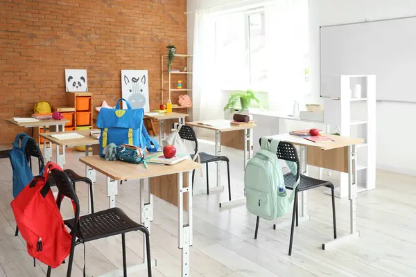 Sıraları ve sırt çantaları olan sınıfın içi.