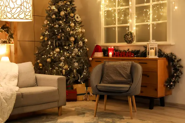 Oturma odasının içinde kanepe, Noel ağacı ve geceleri parlayan ışıklar.