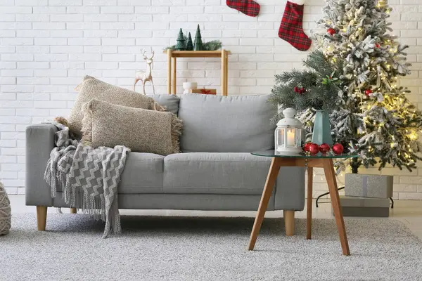 Gri kanepesi, Noel ağacı ve kahve masasında parlayan feneri olan bir oturma odası.