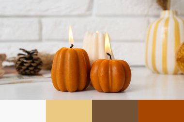 Evdeki beyaz tuğla duvarın yanındaki raf ünitesinde balkabağı şeklinde mumlar yakıyor.