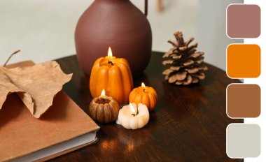 Balkabağı şeklinde mumlar yakmak, sonbahar yaprağı ve kitap evdeki sehpanın üzerinde, yakın çekim.