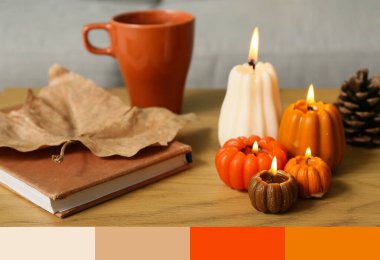 Balkabağı şeklinde mumlar yakmak, çay fincanı ve kitap evdeki sehpanın üzerinde, yakın çekim.