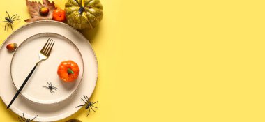 Cadılar Bayramı masa ayarları, balkabaklarıyla sarı arkaplanda örümcekler ve metin için boşluk.