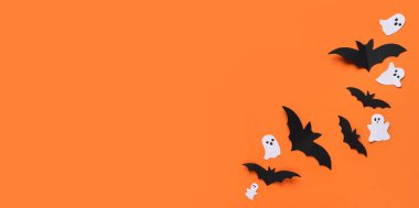 Cadılar Bayramı partisi için kağıt yarasalar ve hayaletler turuncu arka planda ve metin için yer var.