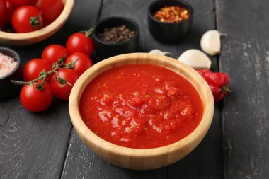 Koyu ahşap arka planda lezzetli domates soslu bir kase.