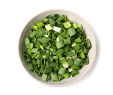 Beyaz arka planda taze kesilmiş yeşil soğanlı kase