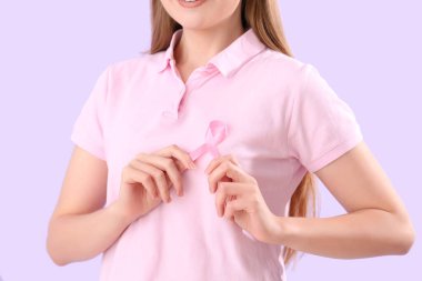 Leylak arka planında pembe kurdeleli genç bir kadın, yakın plan. Göğüs kanseri farkındalığı konsepti