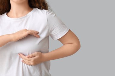 Genç bir kadın göğsünü arka planda kontrol ediyor, yakın plan. Kanser farkındalığı kavramı