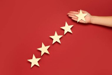 Kırmızı arka planda beş yıldızlı bir kadın eli. Müşteri deneyimi kavramı