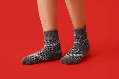 Kırmızı arka planda, sıcak gri çoraplı genç kadın bacakları.