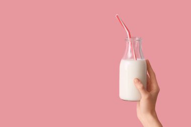 Pembe arka planda saman olan bir şişe süt.
