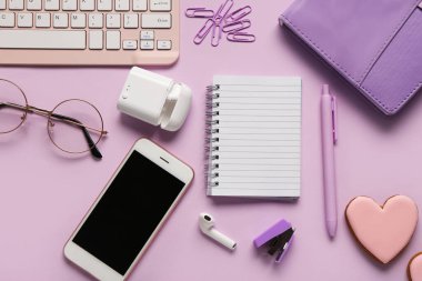 Not defteri, kulaklık ve eflatun kaplamalı telefon kompozisyonu. Üst görünüm