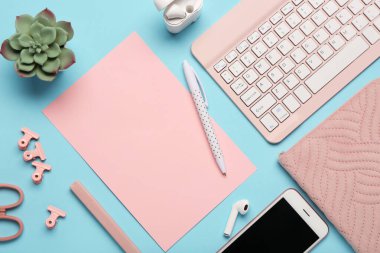 Mavi arka planda pembe kağıt, kalem ve klavye ile kompozisyon. Üst görünüm