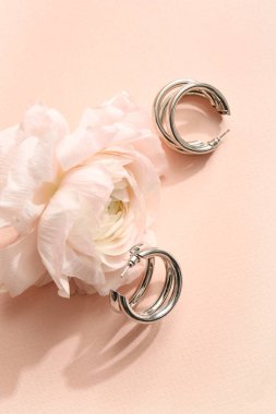 Pembe arka planda gül olan güzel küpeler, yakın plan.