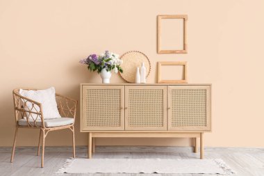 Ahşap sandıkta leylaklar ve odada bej duvarın yanında koltuk.