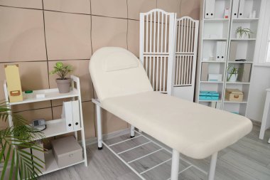 Kanepe, katlanan ekran ve raf üniteleri olan bir tıp bürosu.