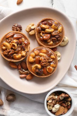 Fındıklı lezzetli tartlar ve tabakta karamel ile grunge beyaz arka plan