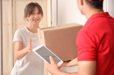 Genç bir kadın teslimatçıdan paket alıyor.