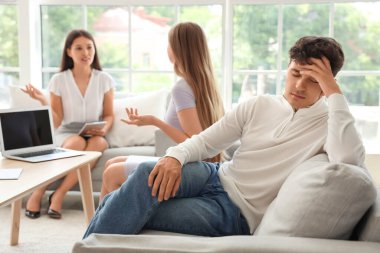 Seksolojistin ofisindeki kanepede oturan üzgün genç adam.