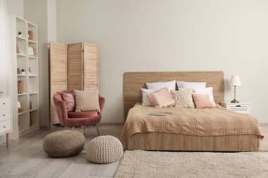 Rahat yatağı, rahat koltuğu ve raf ünitesi olan modern bir yatak odası.