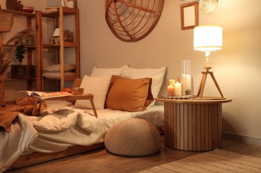 Şık bir yatak odası, rahat bir yatak odası, tepsi masası ve akşam lambaları.