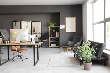 Modern fotoğraf stüdyosunda bilgisayar, kanepe ve ışıklandırma ekipmanlarıyla fotoğrafçılık.