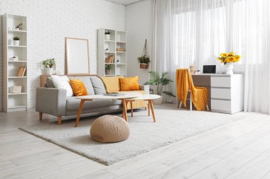 Modern oturma odasının içinde iş yeri ve vazoda ayçiçekleri var.