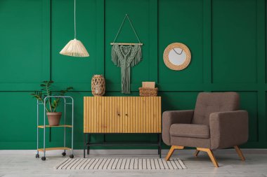 Koltuk, çekmece, ayna ve ev bitkisi oturma odasının içinde.