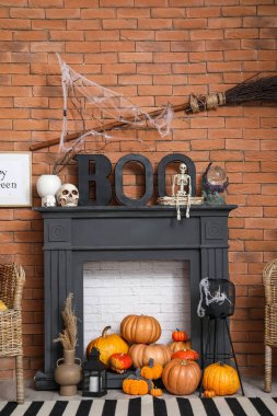 Cadılar Bayramı süslemeleri ve tuğla duvarın yanında balkabakları olan şömine.