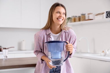 Mutfakta su filtresi sürahisi olan genç bir kadın.