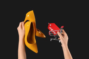 Yüksek topuklu ayakkabı giyen ve arka planda alışveriş arabası olan bir kadın. Kara Cuma İndirimi