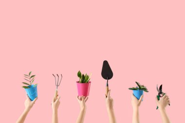 Bahçe aletleri ve pembe arka planda bitkileri olan kadın elleri