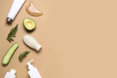 Doğal kozmetik ürünleri, guasha masaj aleti, avokado ve salatalık rengi arka planda.