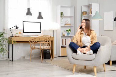 Gri koltukta cep telefonuyla konuşan güzel bir kadın.