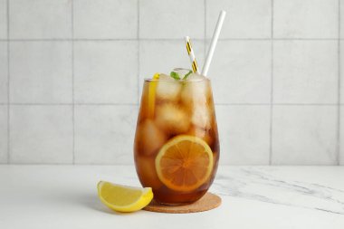 Bir bardak Long Island buzlu çay kokteyli ve beyaz masada nane şekeri.