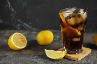 Bir bardak Long Island buzlu çay kokteyli ve koyu renkli limonlar.