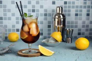 Bir bardak Long Island buzlu çay kokteyli. Nane ve limonlu açık mavi masa.