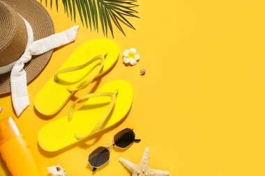 Sarı arka planda şık plaj ayakkabıları ve aksesuarları olan kompozisyon, yakın plan.