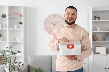 Evde ilk yardım çantası olan genç bir adam var.