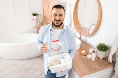 Banyoda ilk yardım çantası olan genç bir adam var.