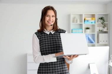 Ofiste dizüstü bilgisayarı olan kulaklık takan kadın teknik destek ajanı.