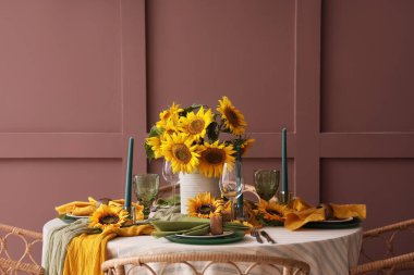 Tabaklar, mumlar ve güzel ayçiçekleri olan zarif bir masa.