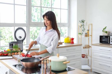 Genç bir kadın mutfakta taze dolmalık biber kesiyor.