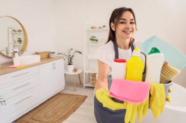 Tuvalette temizlik malzemesi taşıyan kadın hademe.