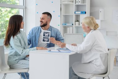 Ultrason görüntüsü olan genç bir çift klinikteki tüp bebek doktorunu ziyaret ediyor.