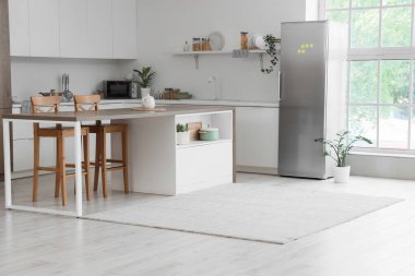 Modern buzdolabı, tezgah ve masa olan mutfağın içi.